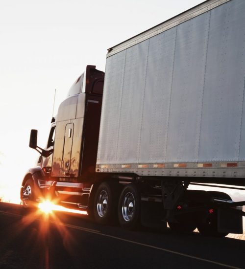 silhouette-of-a-commercial-truck-driving-on-a-highway-at-sunset-.jpg